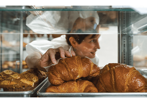 La propietaria de Empire Baking, Meaders Ozarow, tomando un croissant para un cliente.