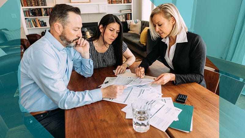 Asesor reuniéndose con una pareja para analizar proyecciones financieras